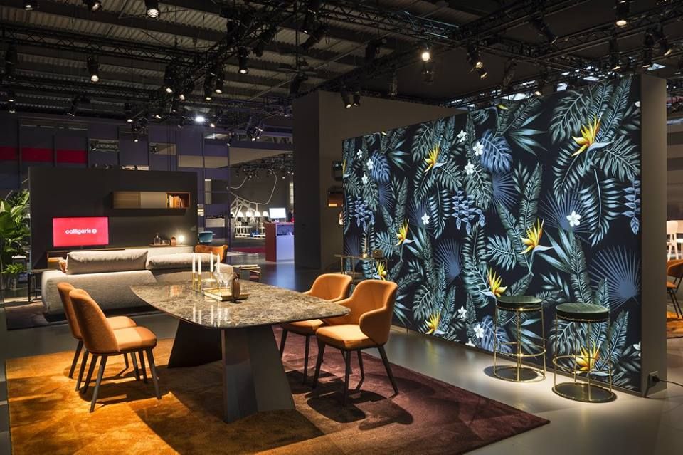 Zona pranzo con parete floreale, tavolo, sedie e soggiorno sullo sfondo.