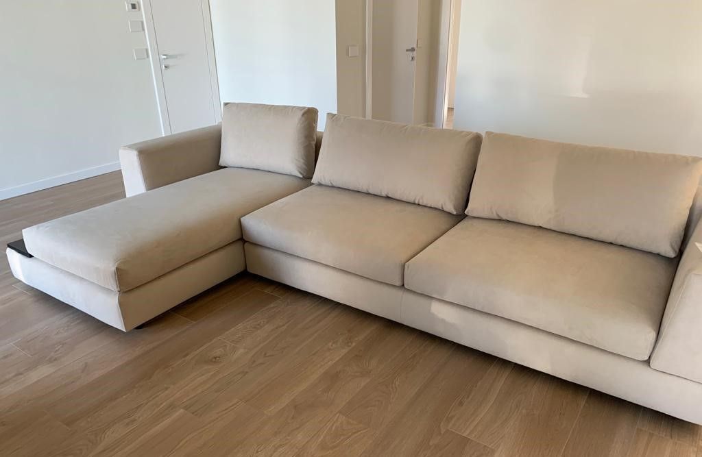 Divano componibile beige in una stanza con pavimenti in legno.