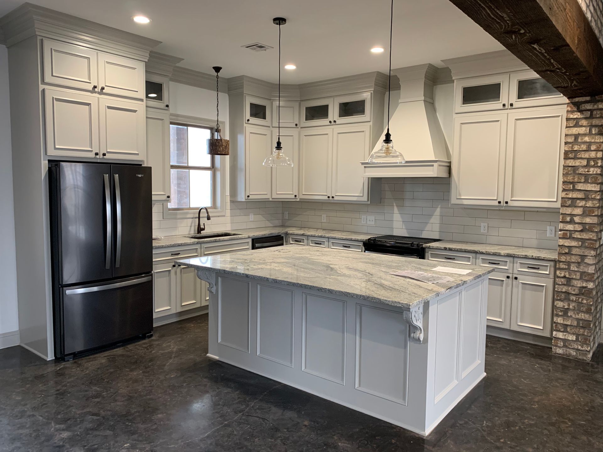 A kitchen with white cabinets , granite counter tops , and a large island.