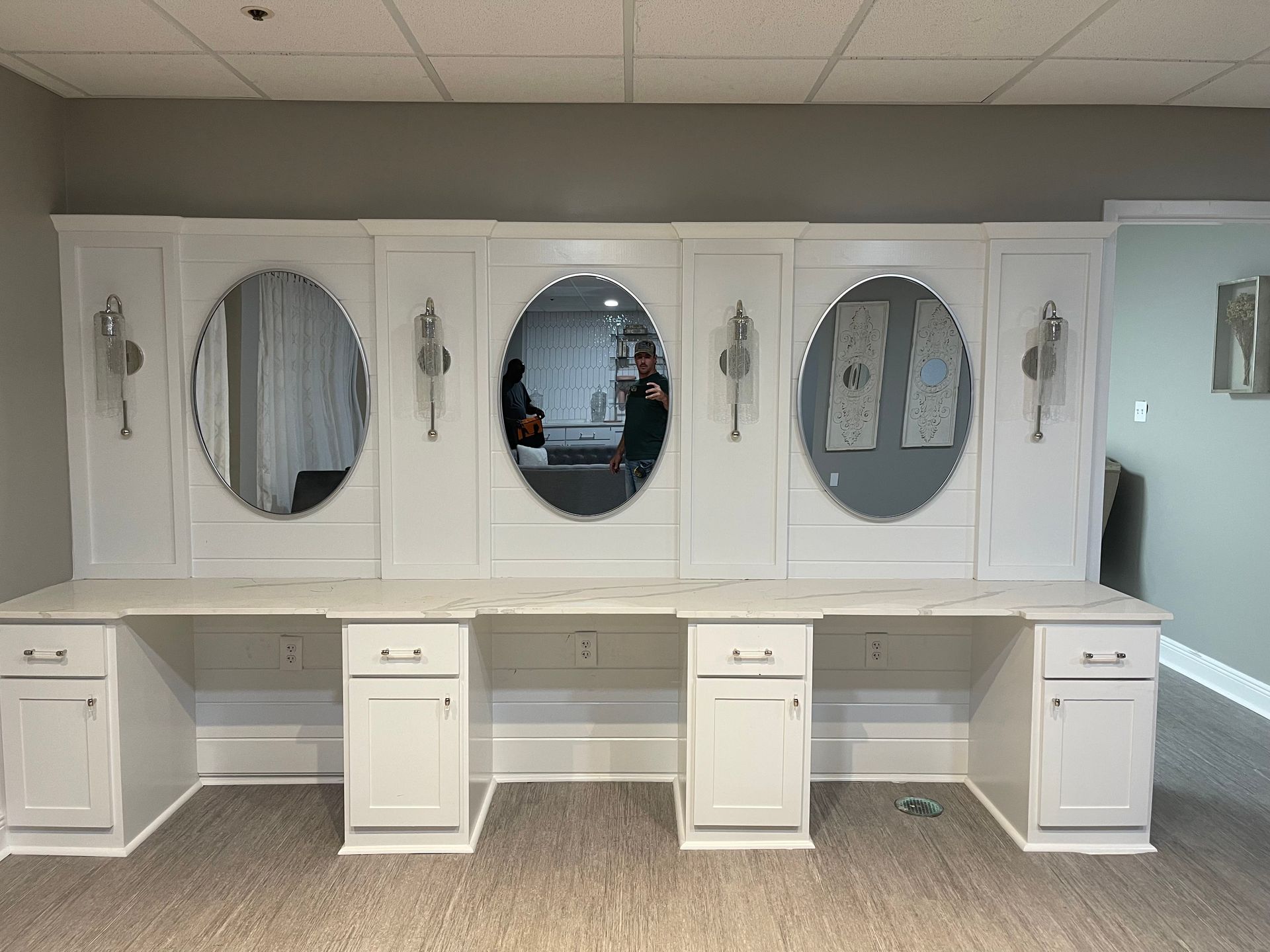 A row of white desks with mirrors on the wall.