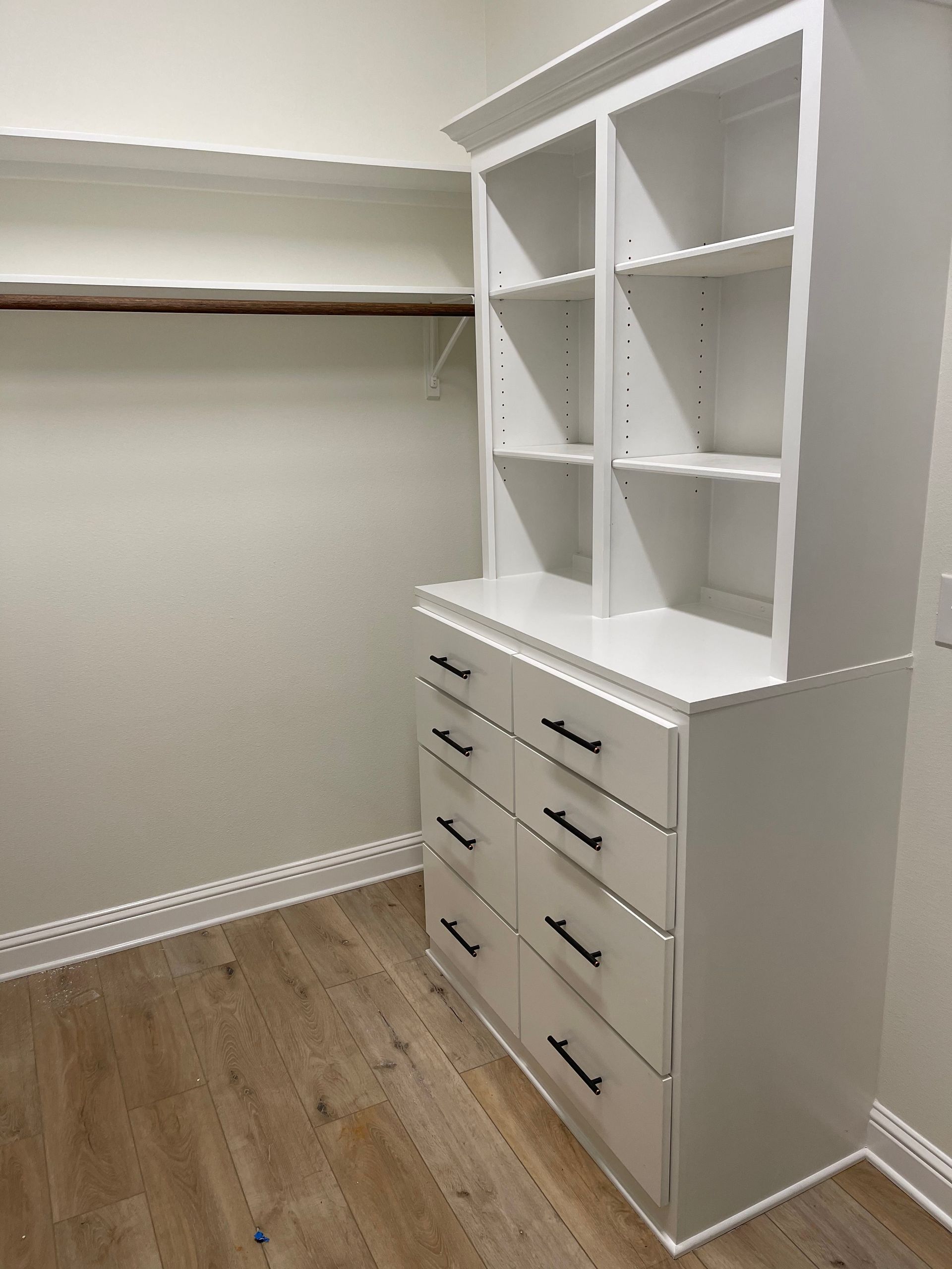 A walk in closet with a dresser and shelves.