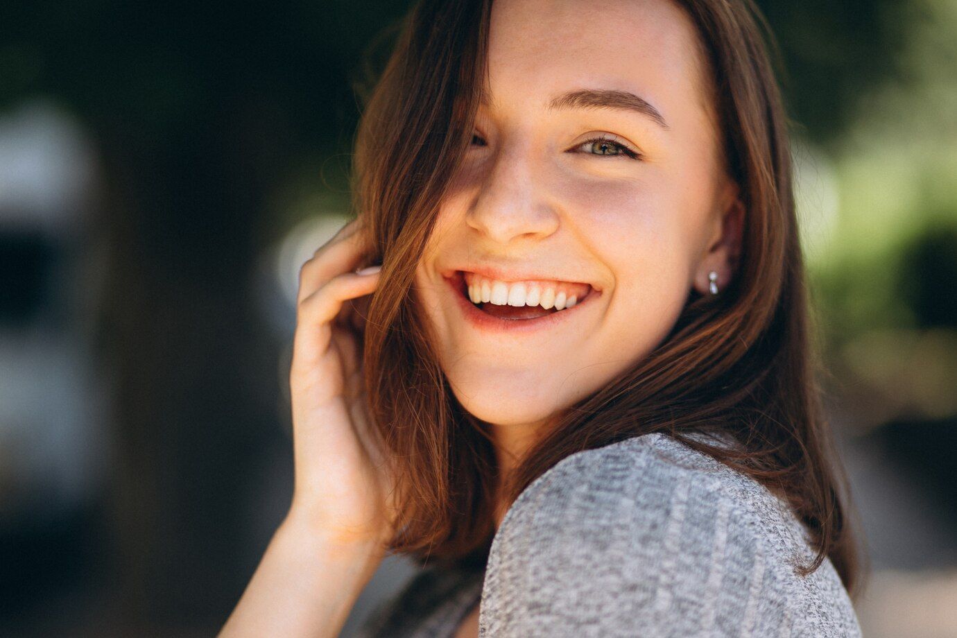 A close up of a woman smiling with her hand in her hair.