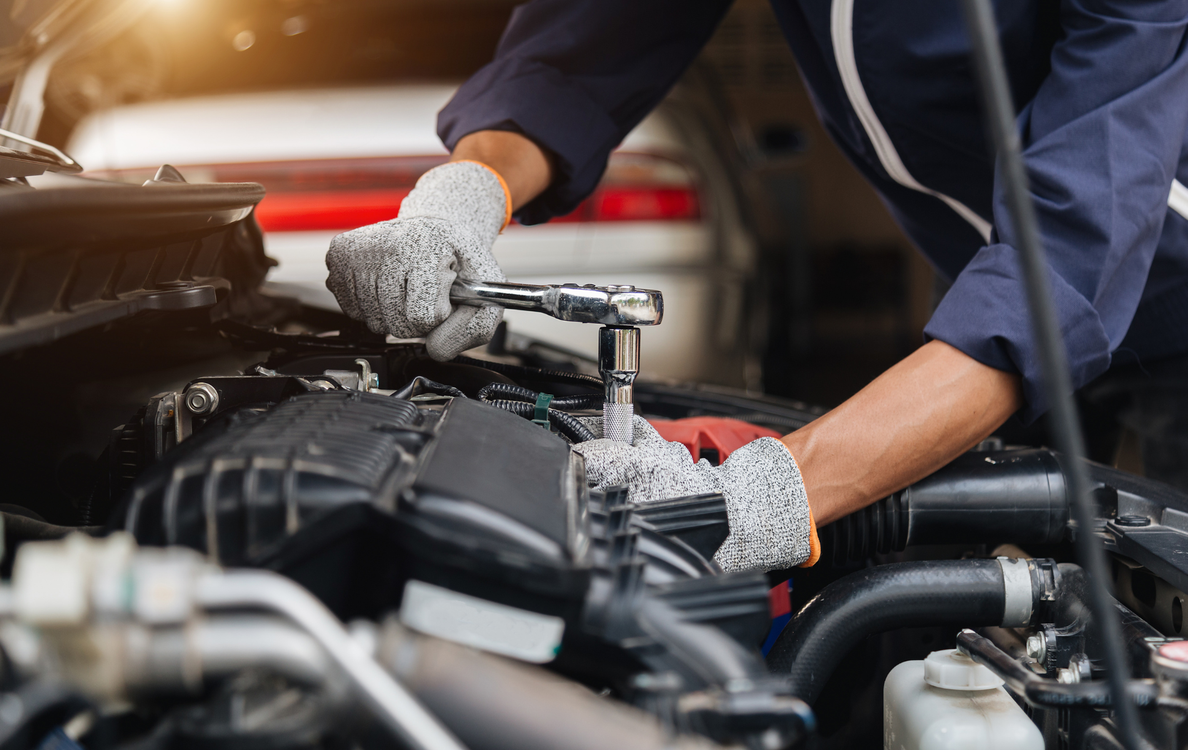 A mechanic is working on the engine of a car in a garage.