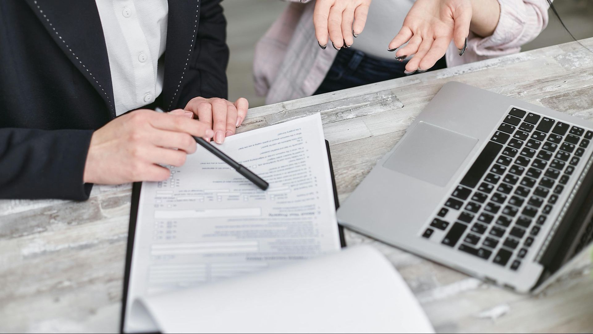 A group of people are sitting at a table with a laptop and papers.