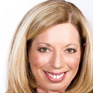 A close up of a woman 's face with blonde hair smiling.