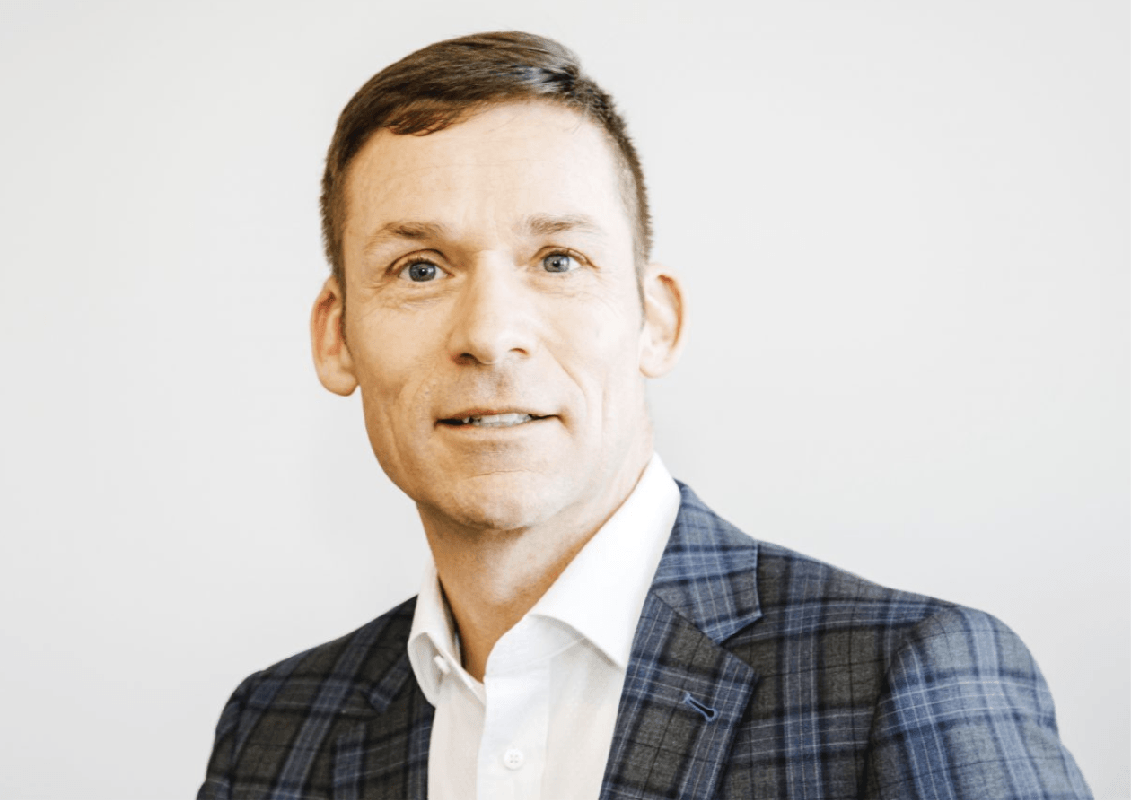 A man in a suit and white shirt is smiling for the camera.