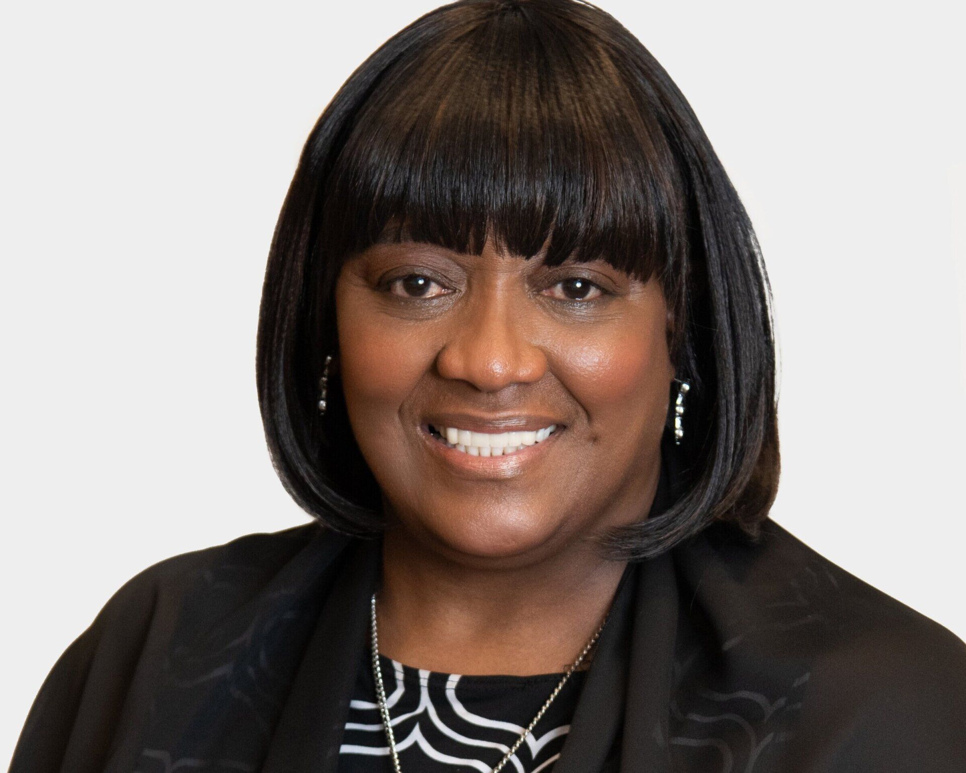 A woman with short hair and bangs is smiling for the camera.