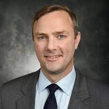 A man in a suit and tie is smiling for the camera.