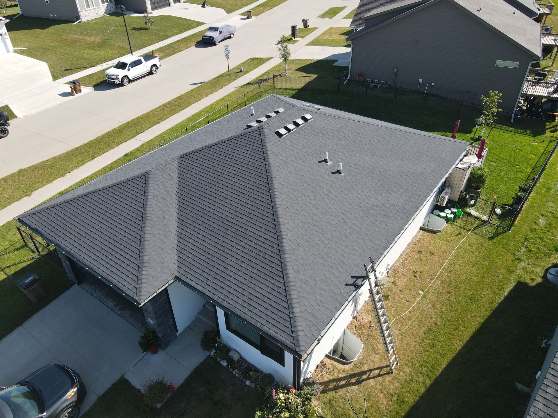 An aerial view of a house with a black roof in a residential area.
