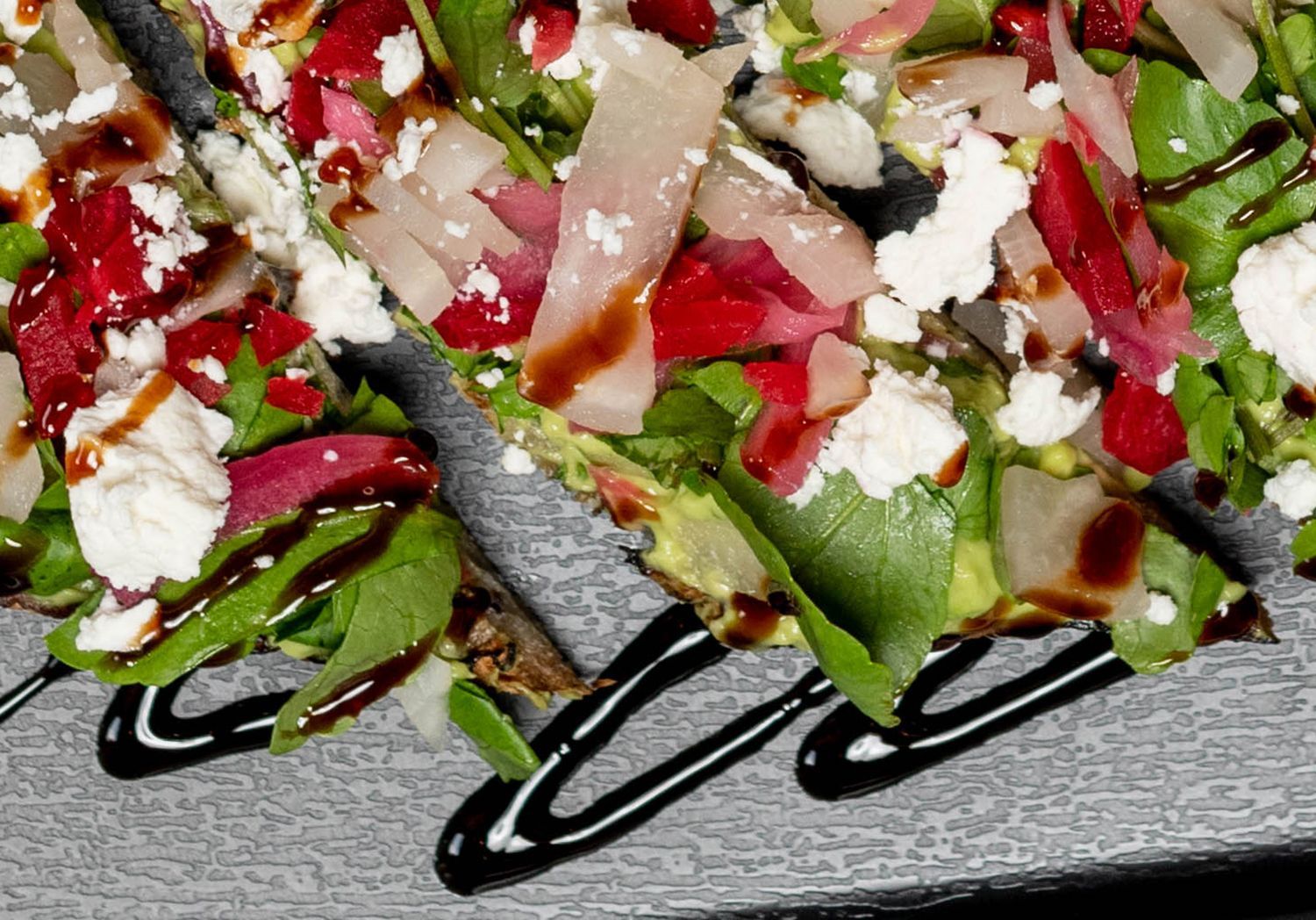 A close up of a salad on a plate with balsamic drizzle