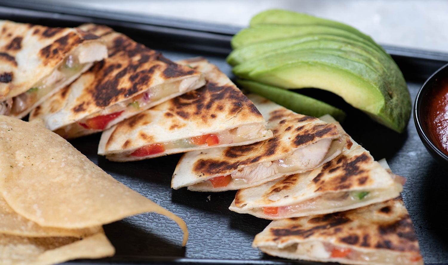 A close up of a plate of food with quesadillas and avocado.