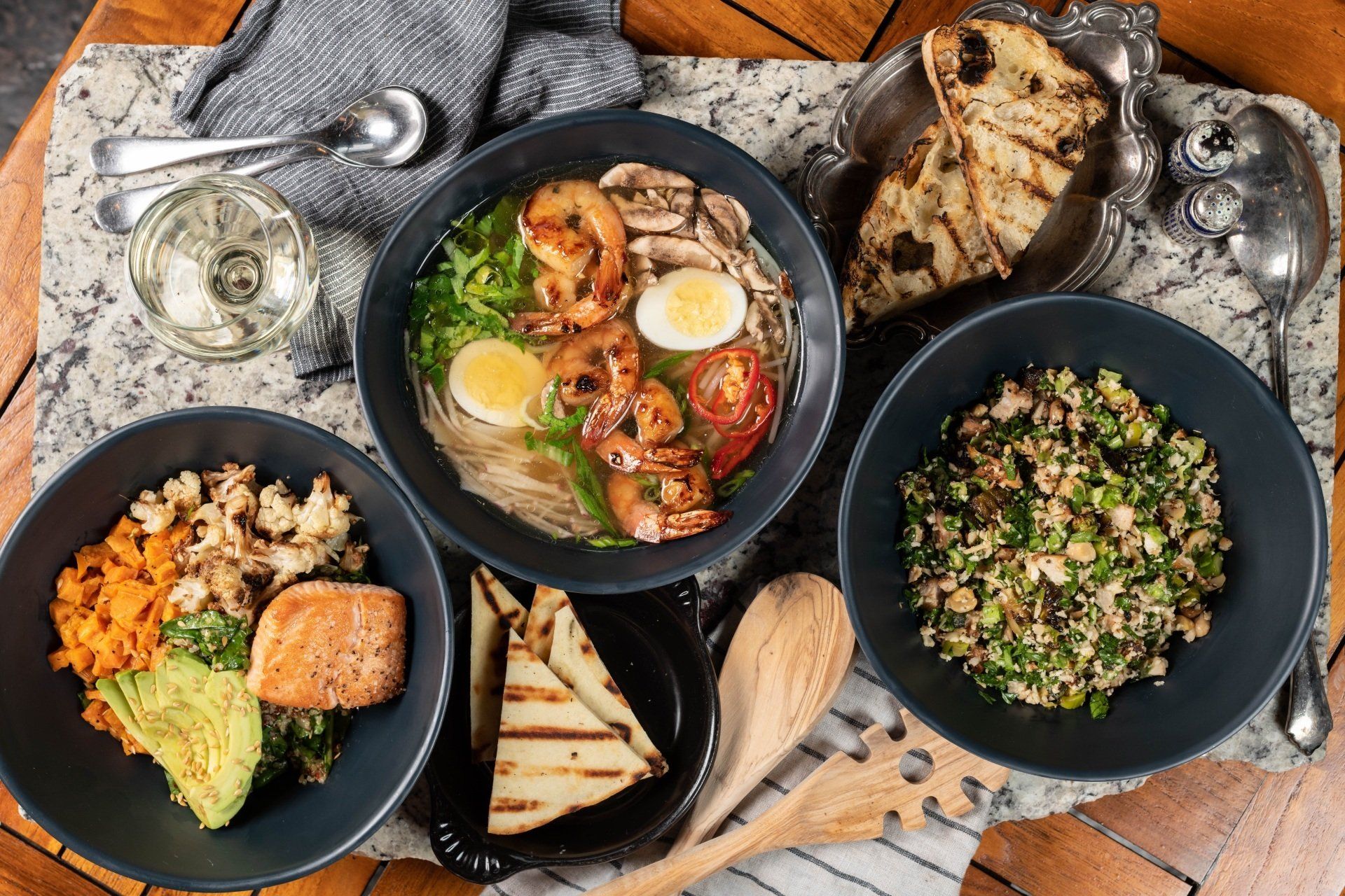 A table topped with bowls of food and utensils.