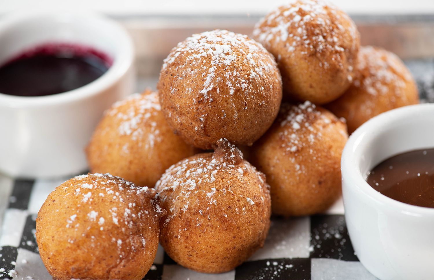 A tray of doughnuts with powdered sugar and chocolate sauce.
