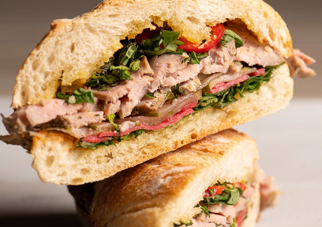 Two sandwiches are stacked on top of each other on a table.