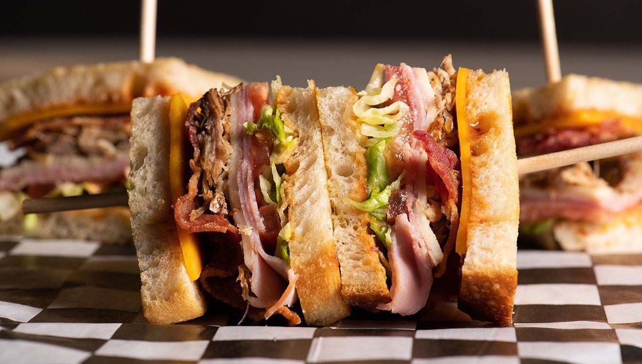 A club sandwich is sitting on a checkered table.