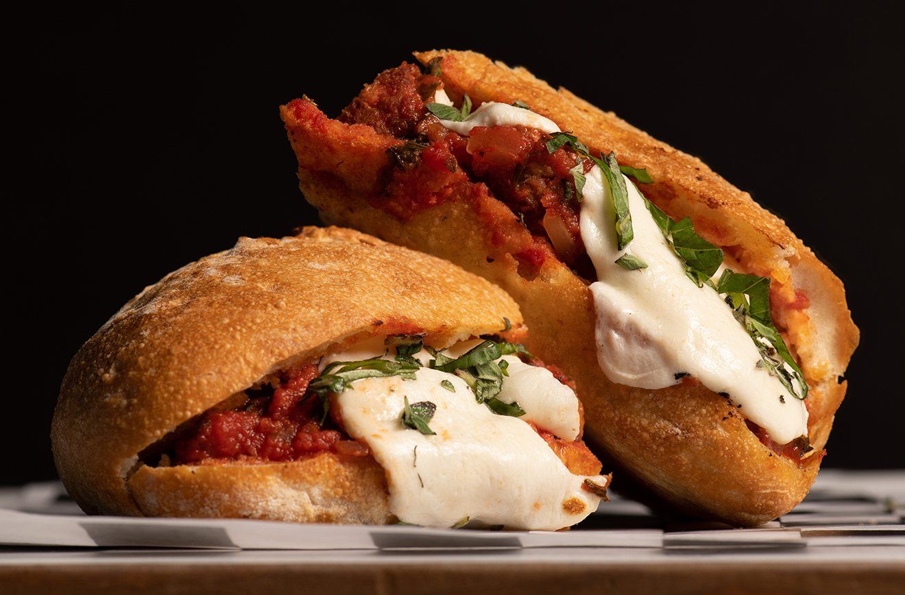 Two sandwiches are sitting on a white plate on a table.