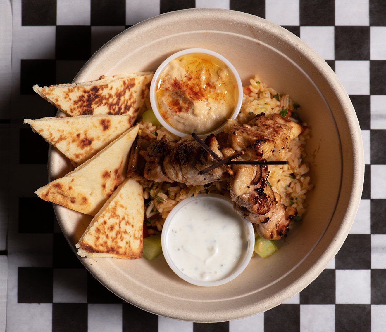 A bowl of food is sitting on a checkered table cloth.