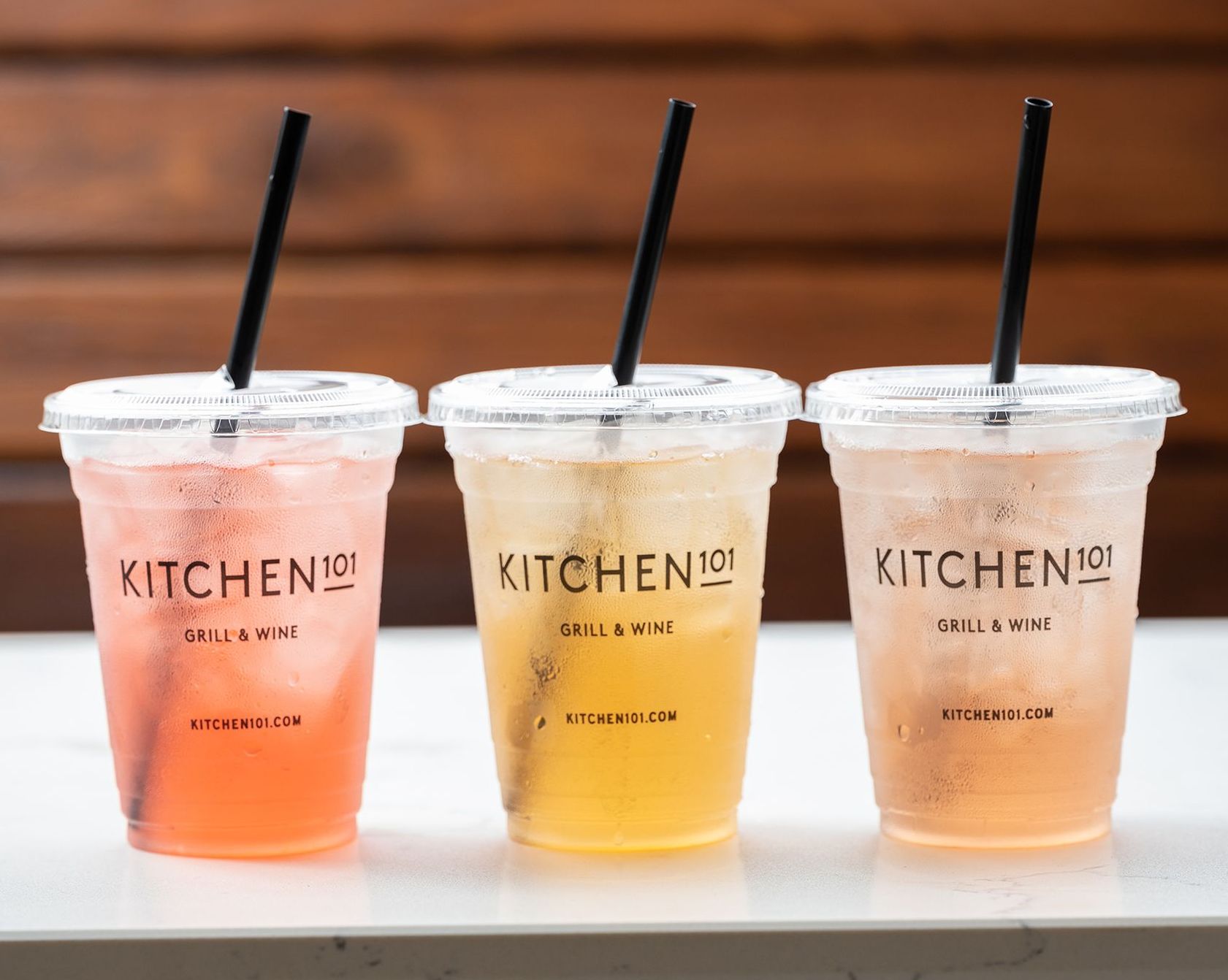 Three cups of drinks with straws are sitting on a table.