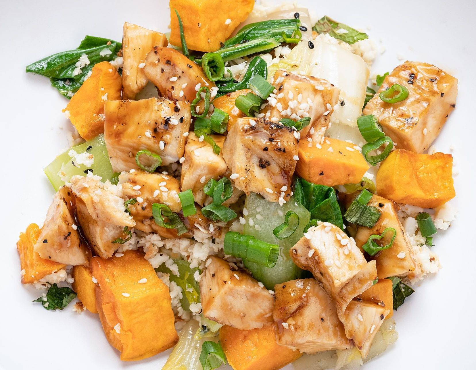 A close up of a plate of food with chicken and vegetables on a table.