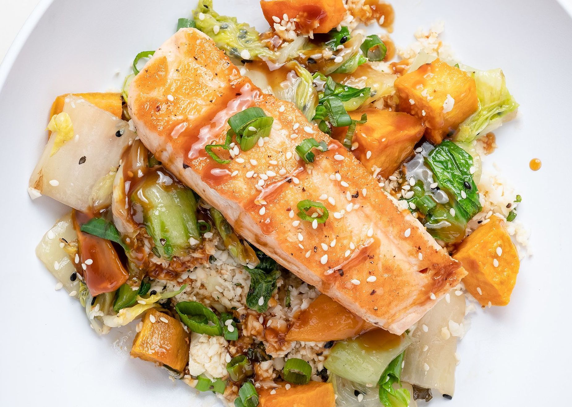 A white plate topped with salmon , rice and vegetables.