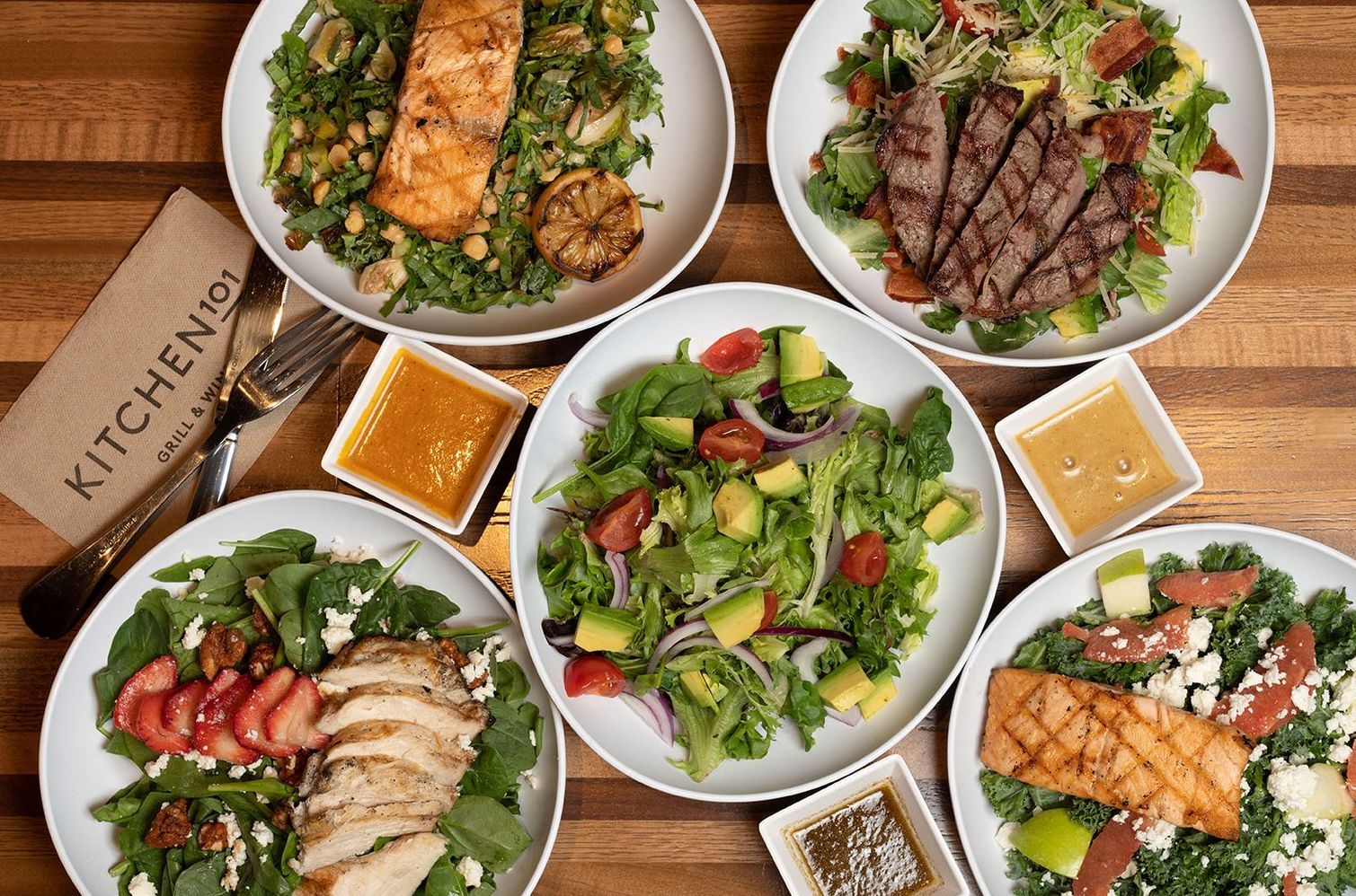 A wooden table topped with plates of food and salads.