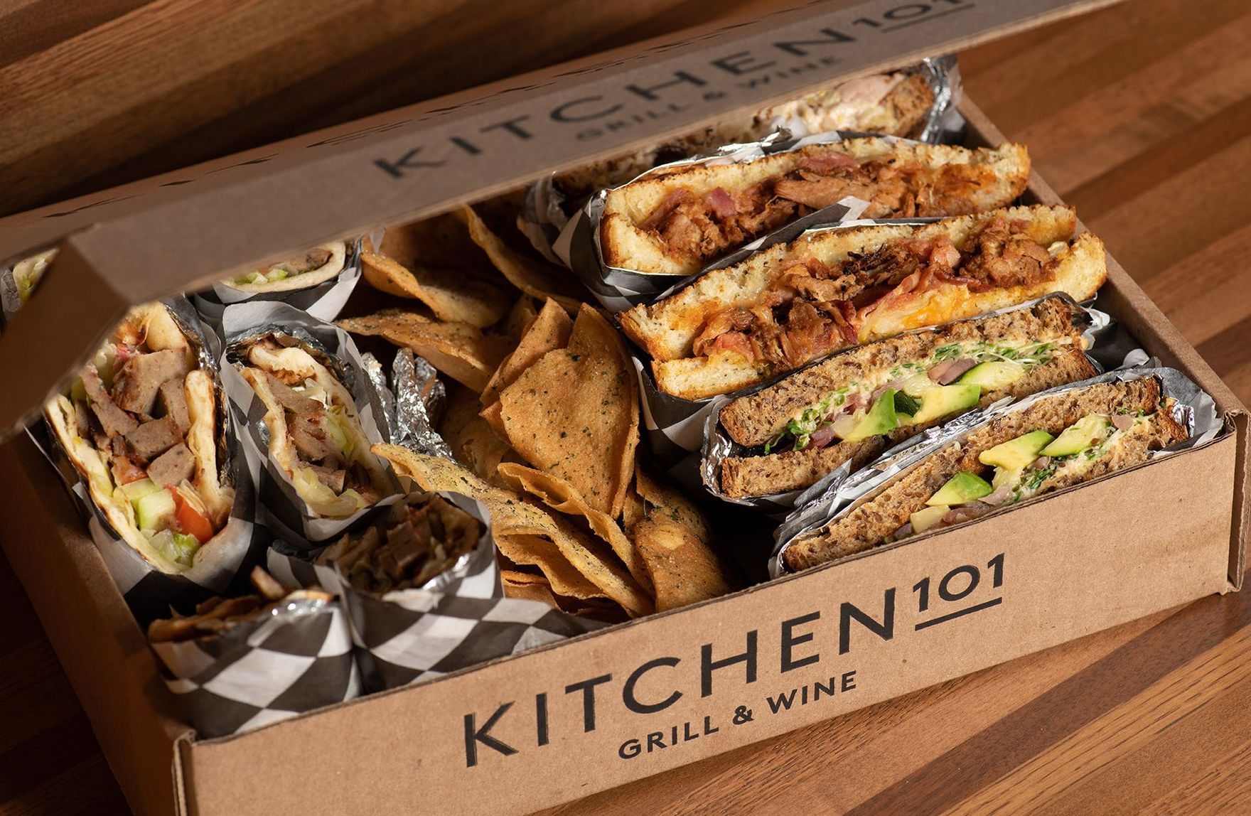 A box filled with sandwiches and chips from kitchen 101