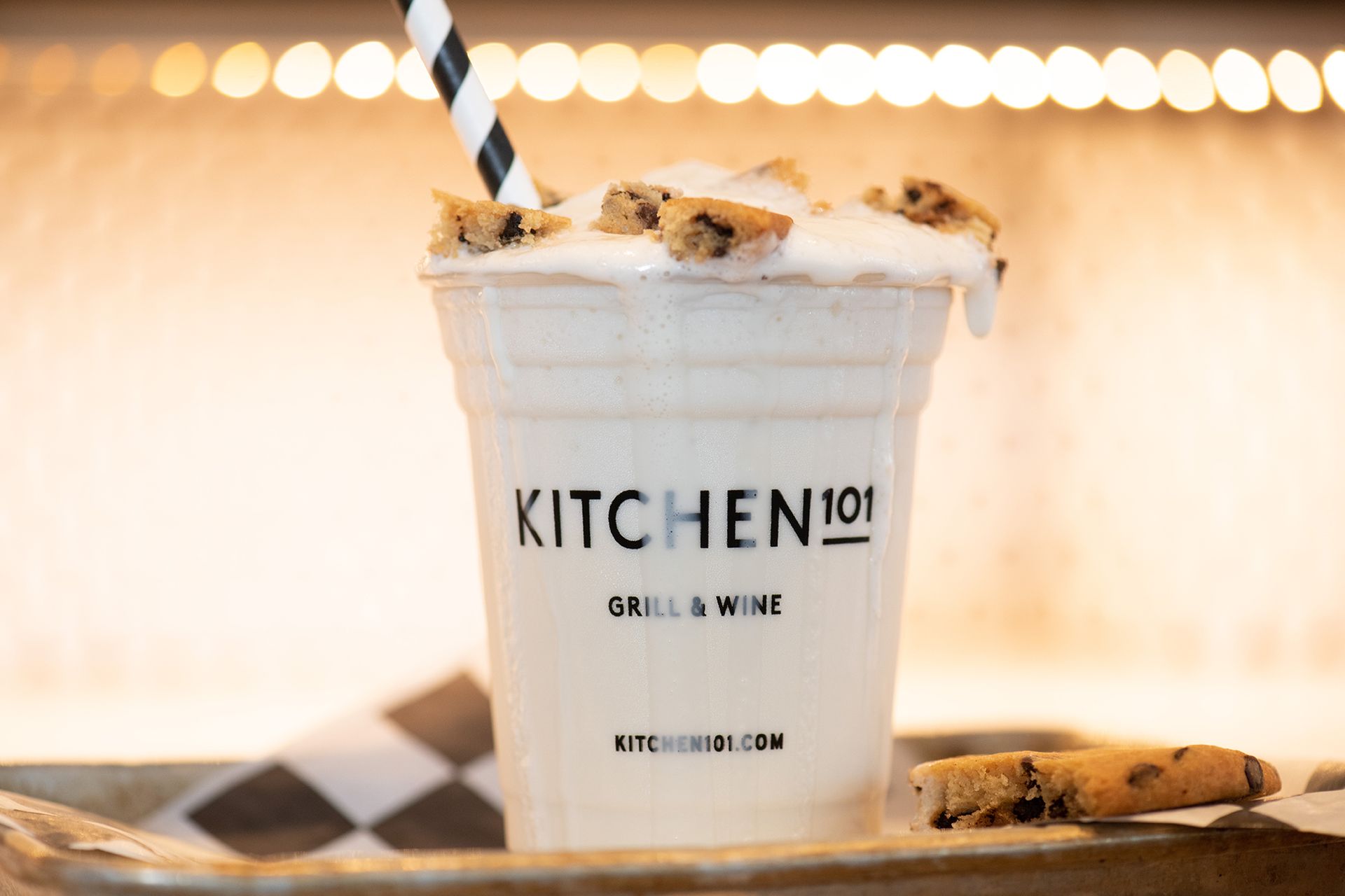 A milkshake in a kitchen 101 cup with a straw and cookies on top.