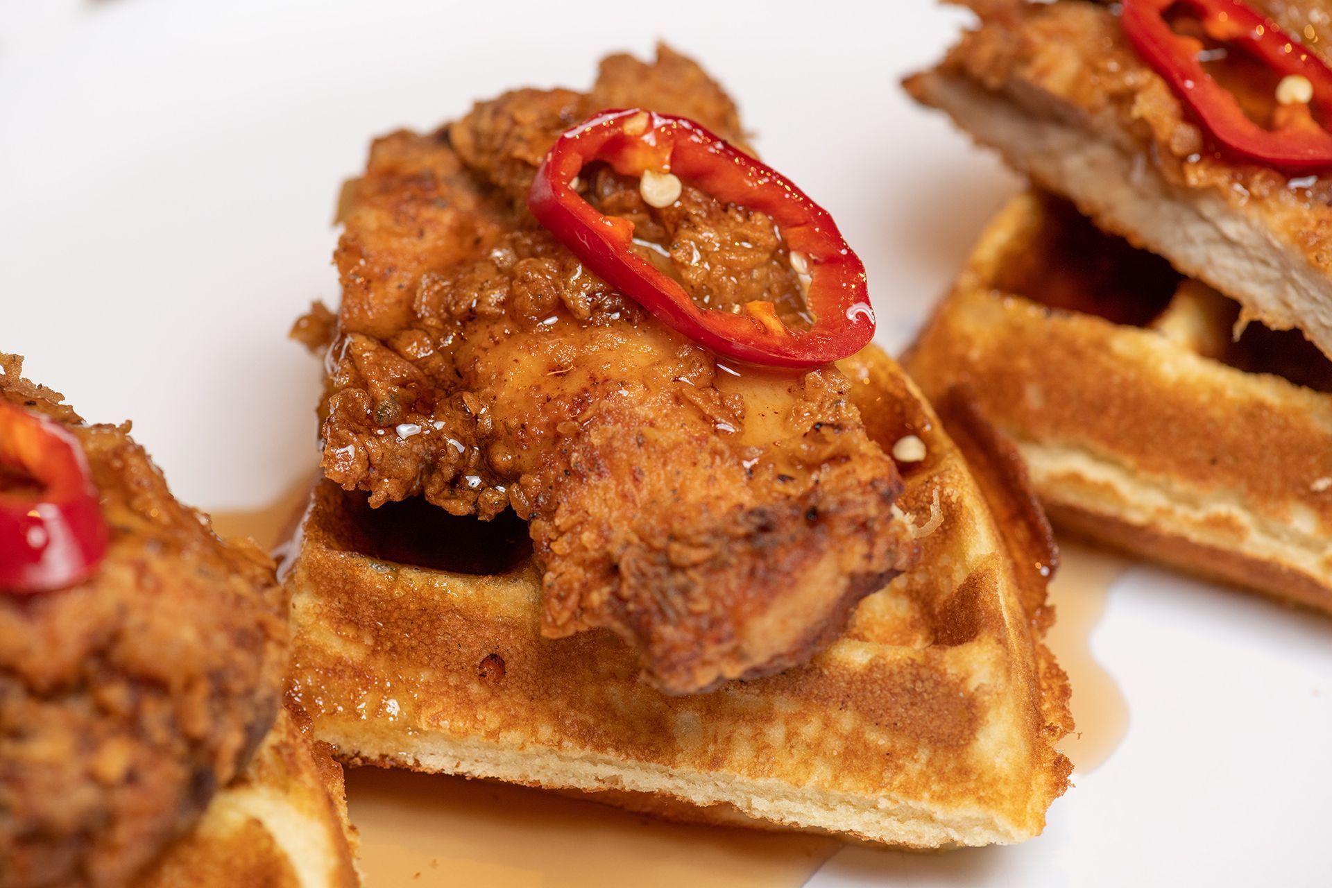 A close up of fried chicken and waffles on a white plate.
