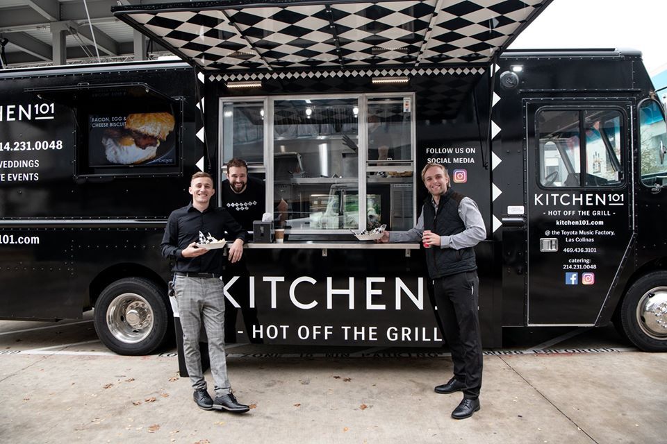 Three men are standing in front of a kitchen hot off the grill food truck.