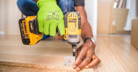 A man is using a drill to drill a hole in a piece of wood.