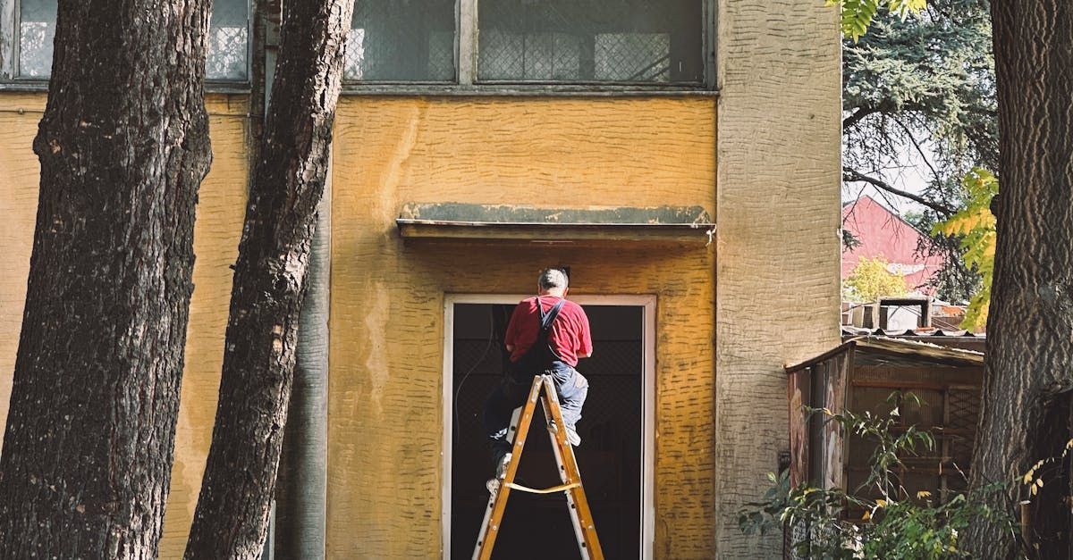 A man is sitting on a ladder in front of a building.