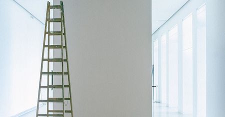 A wooden ladder is leaning against a wall in a hallway