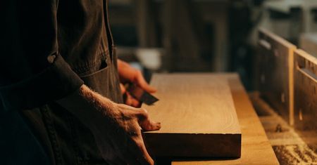 A man is cutting a piece of wood with a saw.