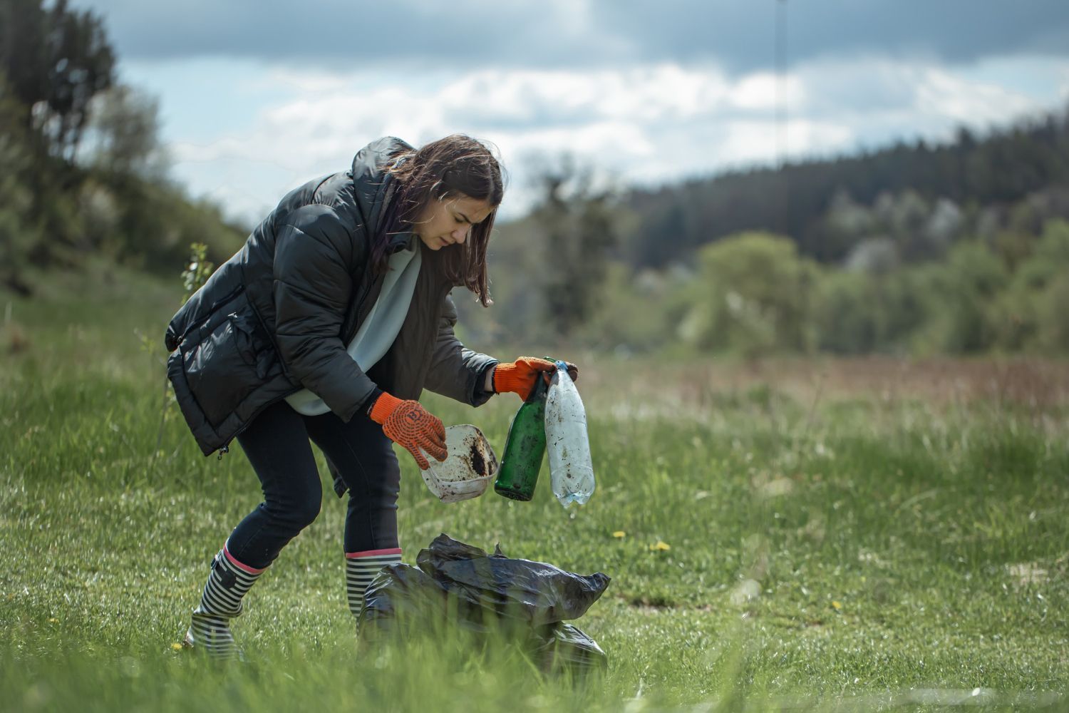 A person is cutting a bush with a pair of scissors.