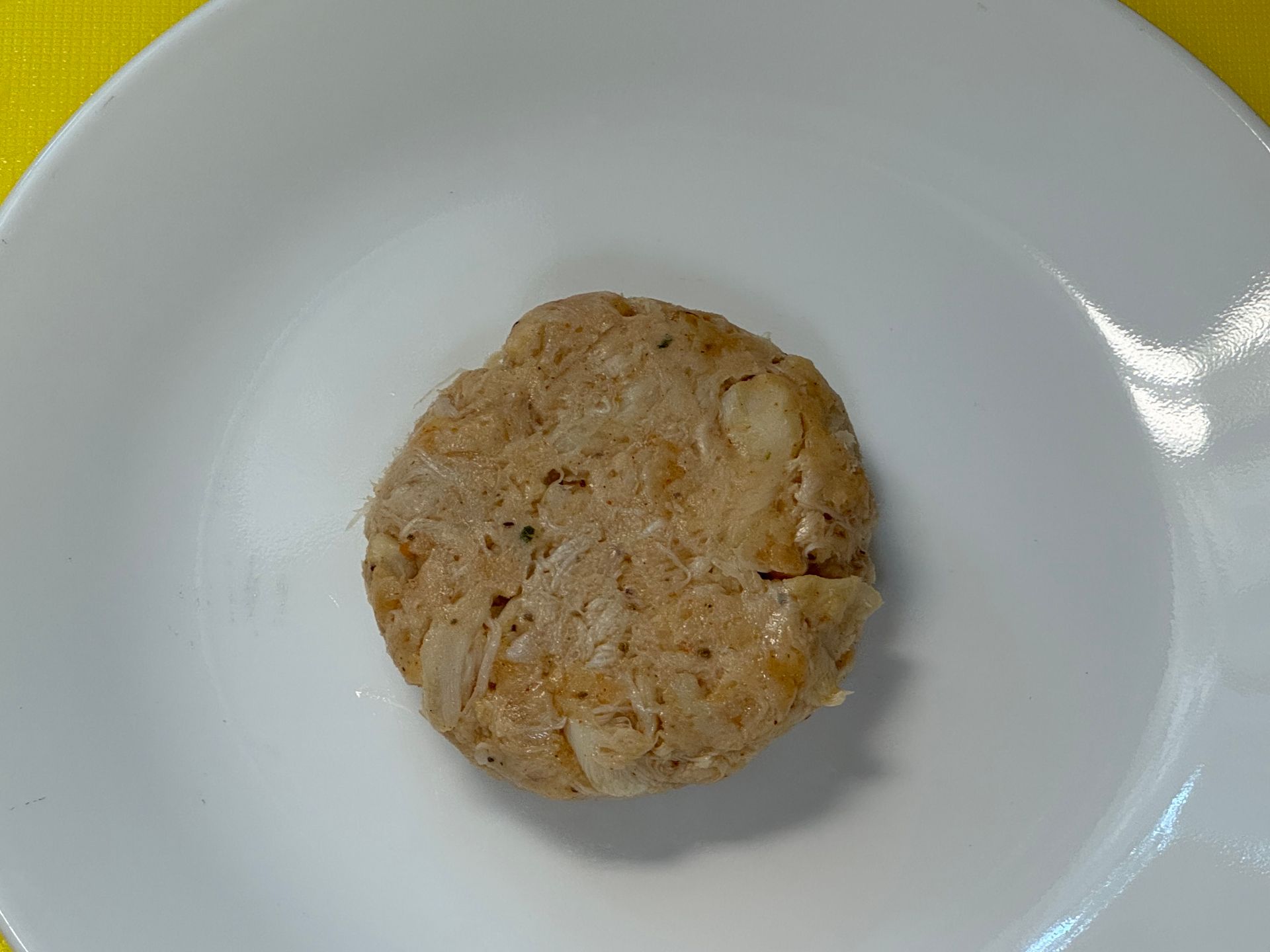 A white plate with a cookie on it on a yellow table