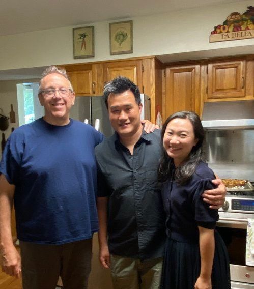 Two men and a woman are posing for a picture in a kitchen