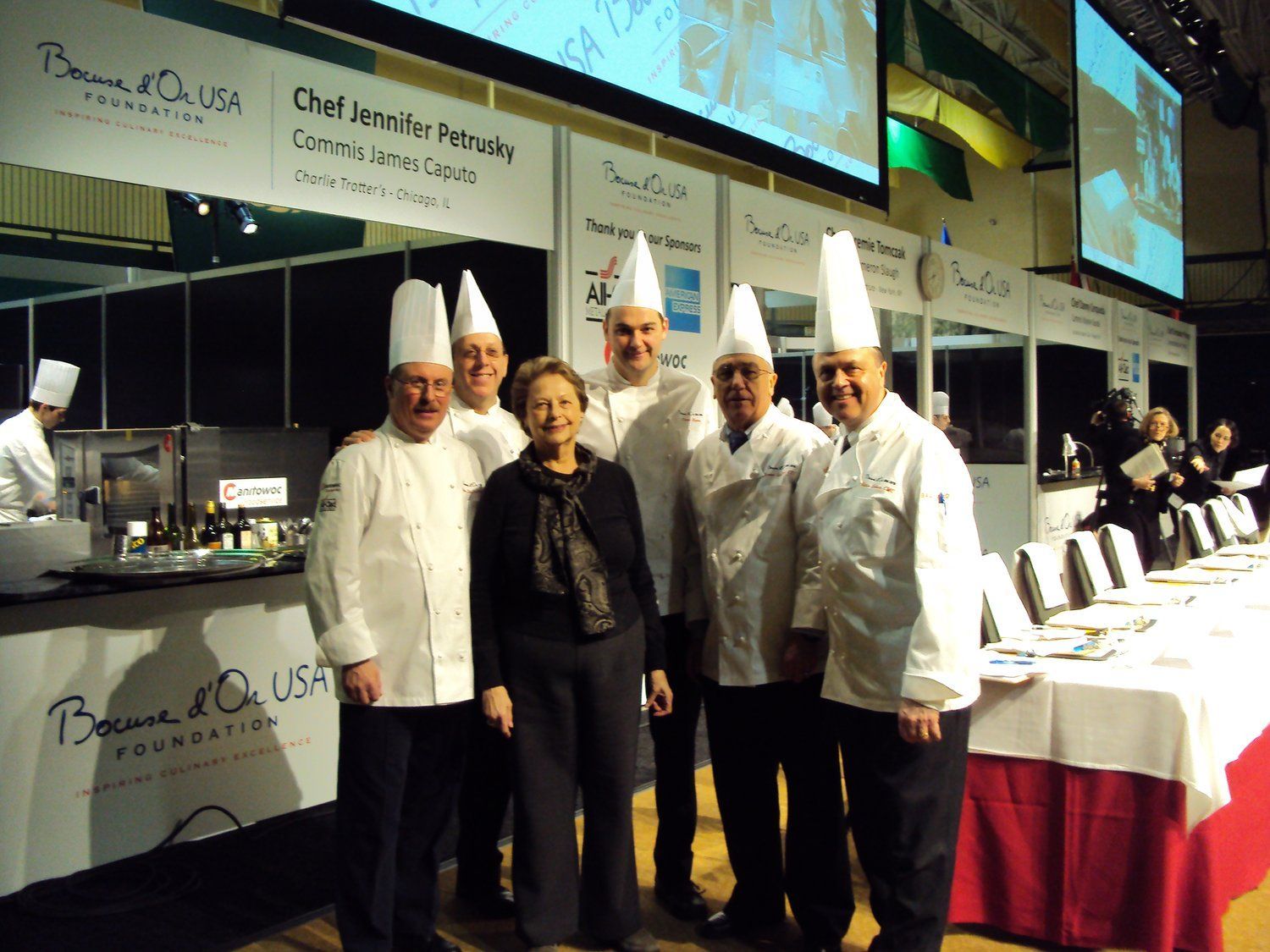 A group of chefs pose for a photo in front of a sign that says chef