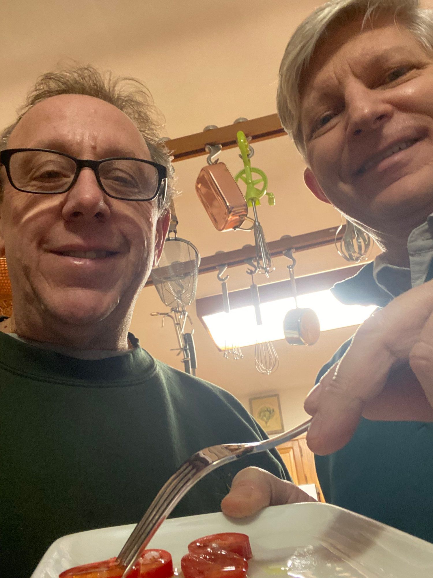 Two men are posing for a picture with a plate of food