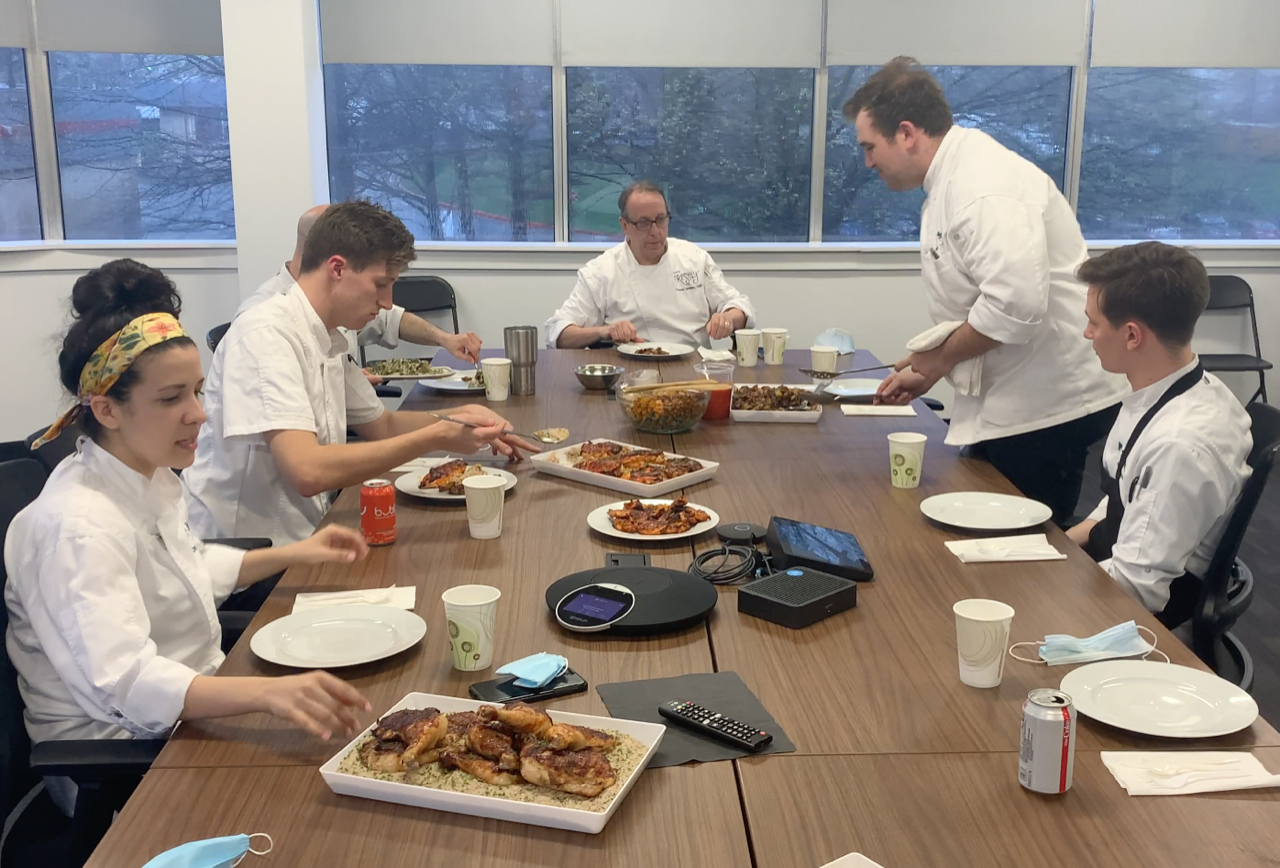 A group of people are sitting around a table eating food.