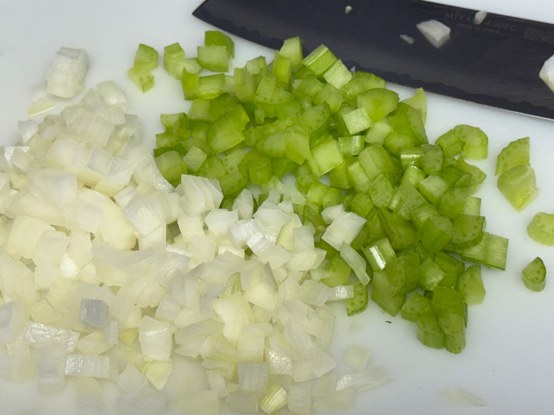 A pan filled with chopped onions is cooking on a stove.
