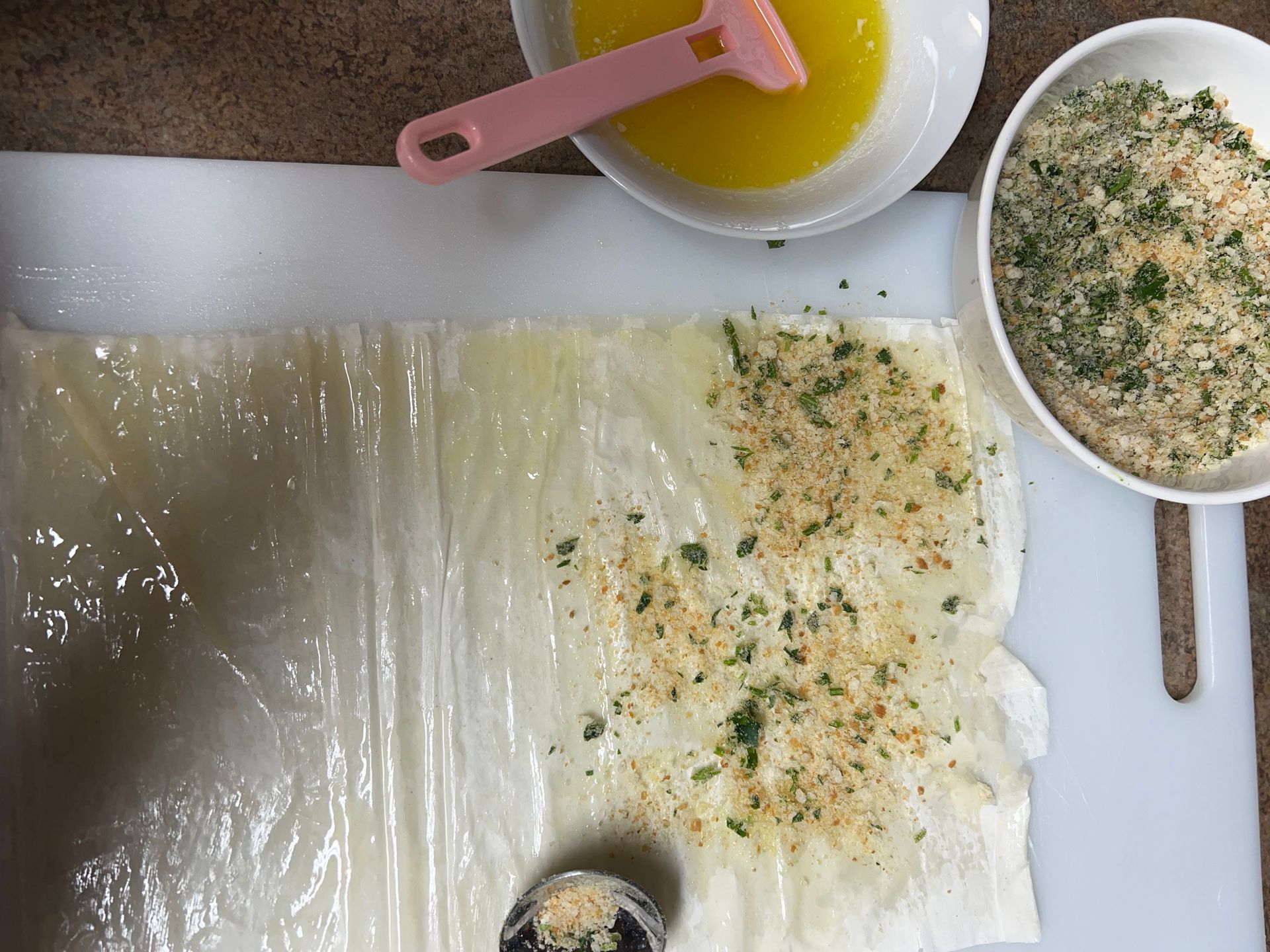 A cutting board with a spoon and bowls of ingredients on it