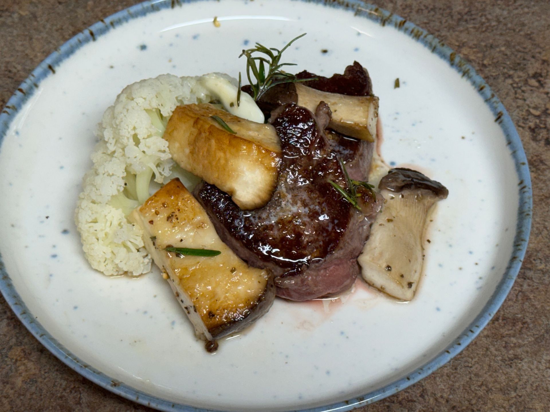 A white plate topped with a large piece of steak