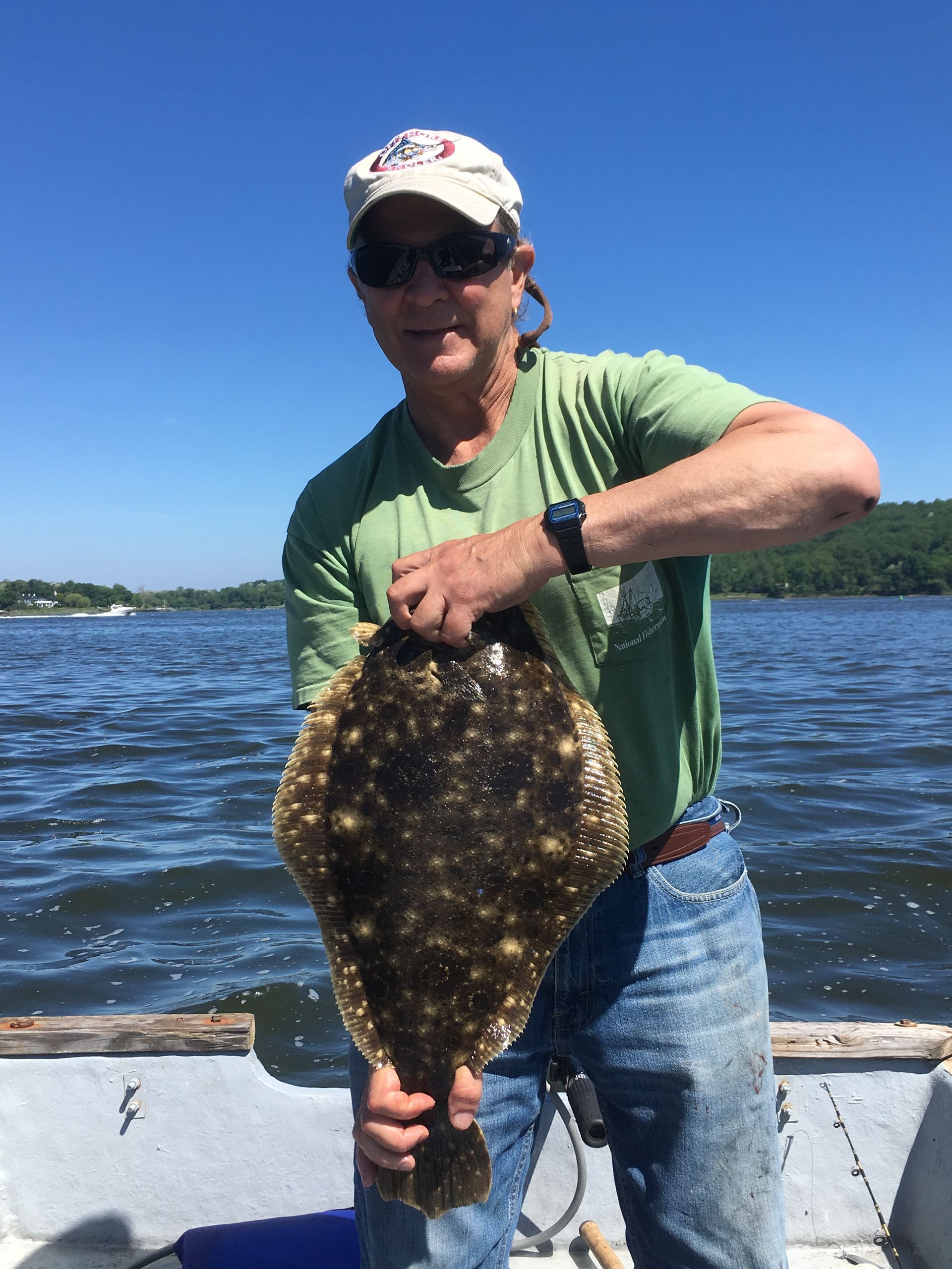 A man is holding a large fish on a boat.