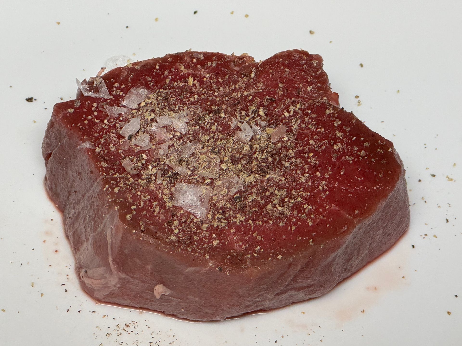 A large piece of meat on a plate with herbs and garlic