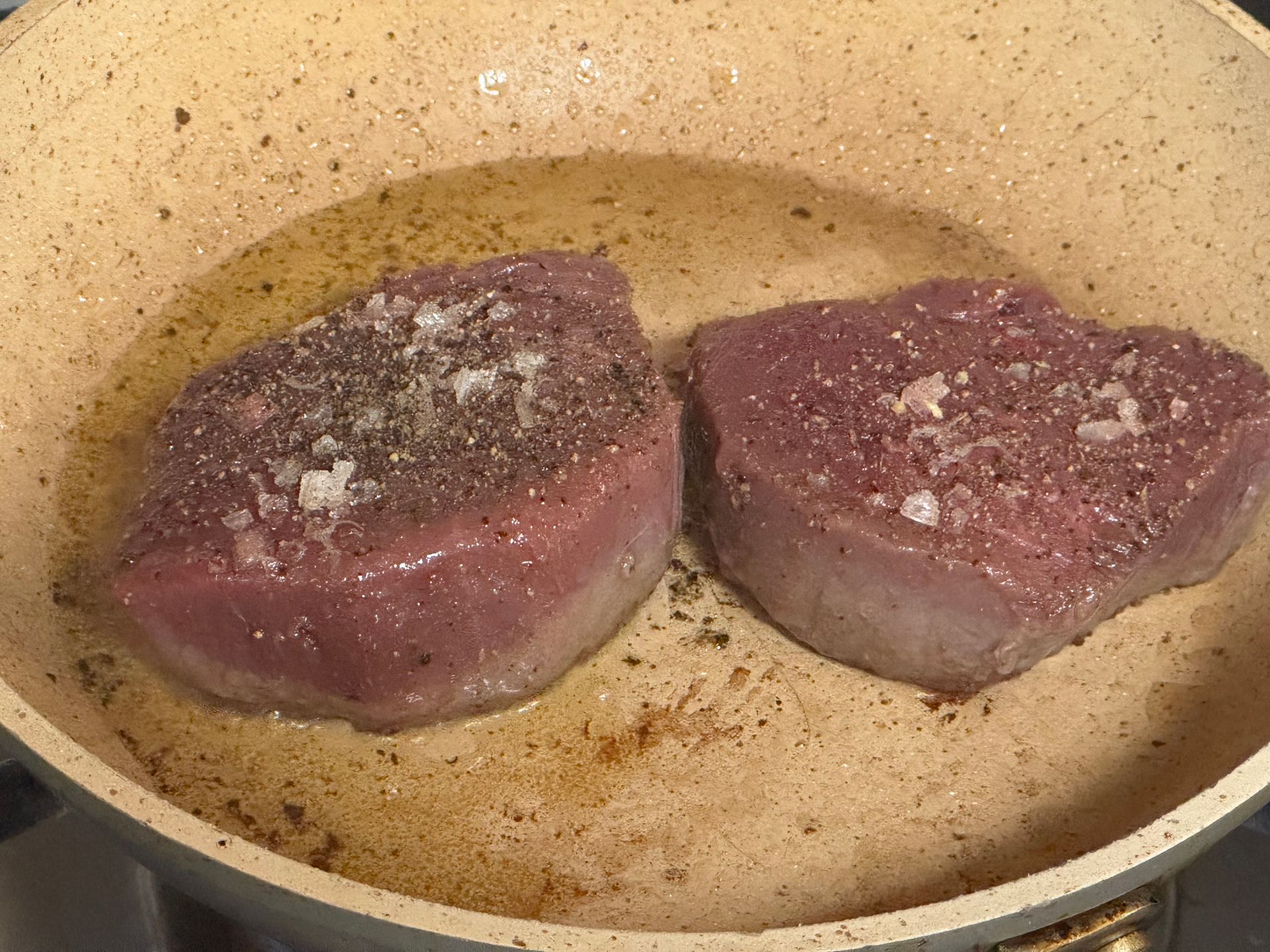 A large steak is being cooked on a grill.