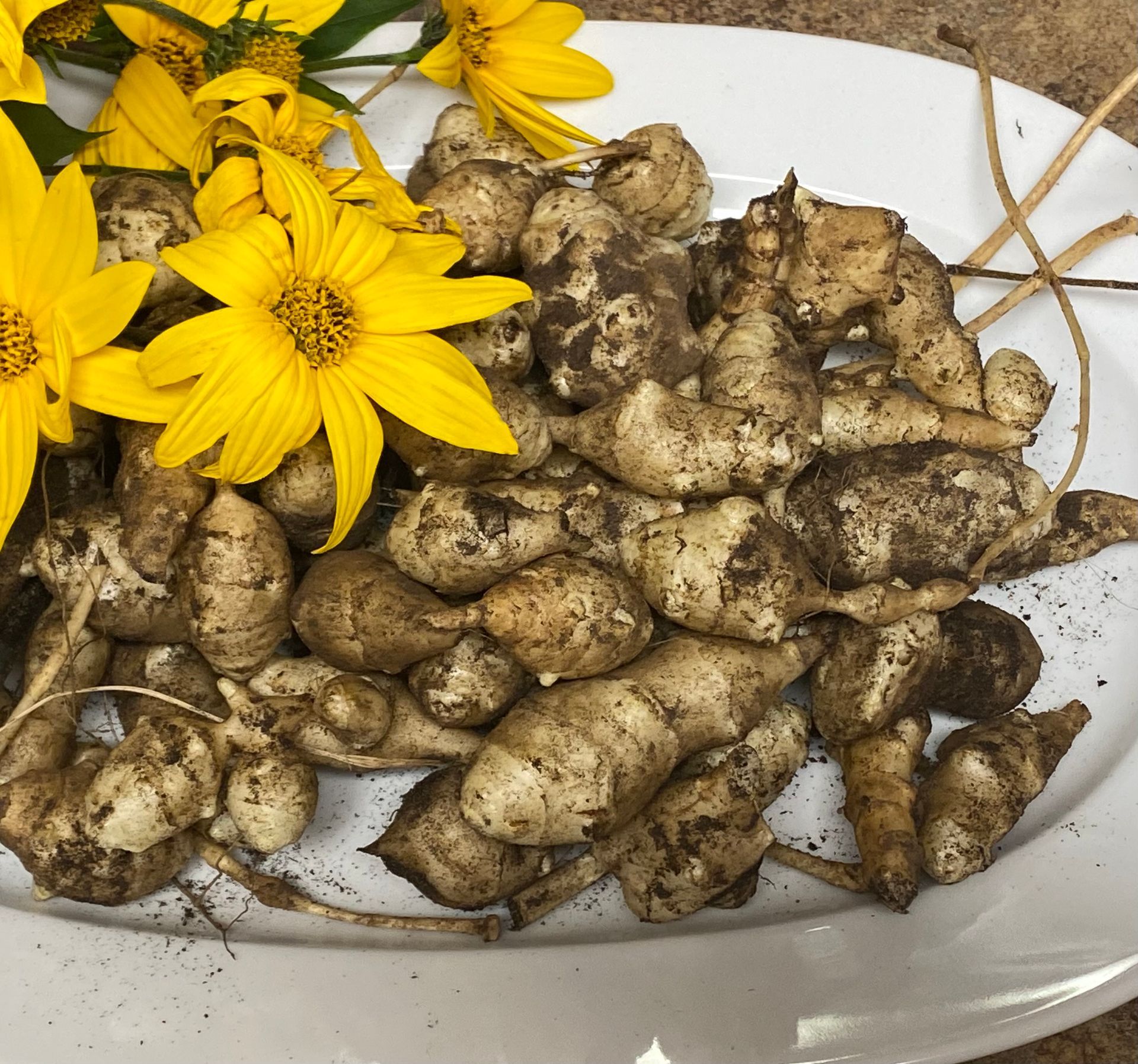 A white plate topped with potatoes and yellow flowers