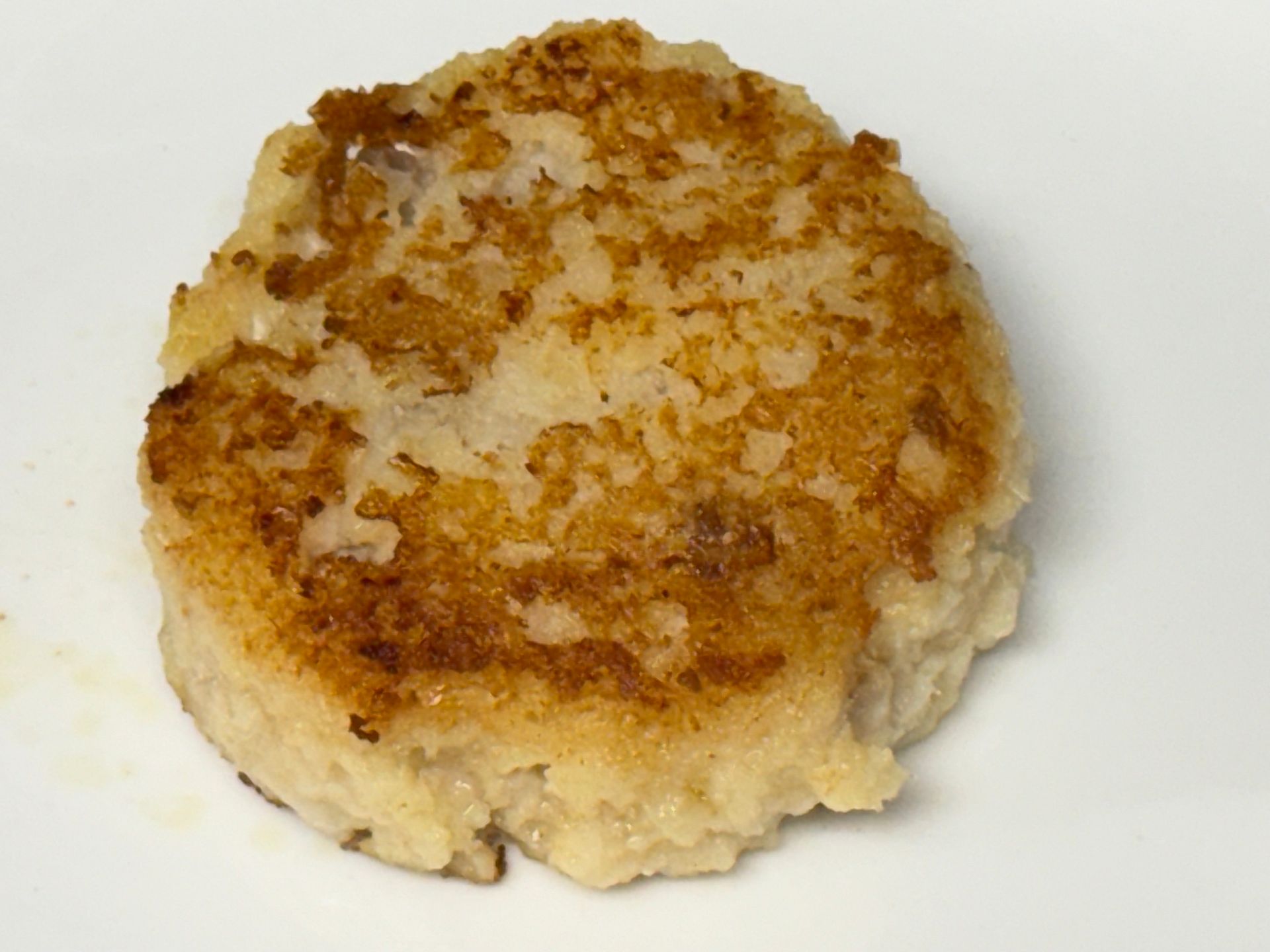 A close up of a fried patty on a white plate