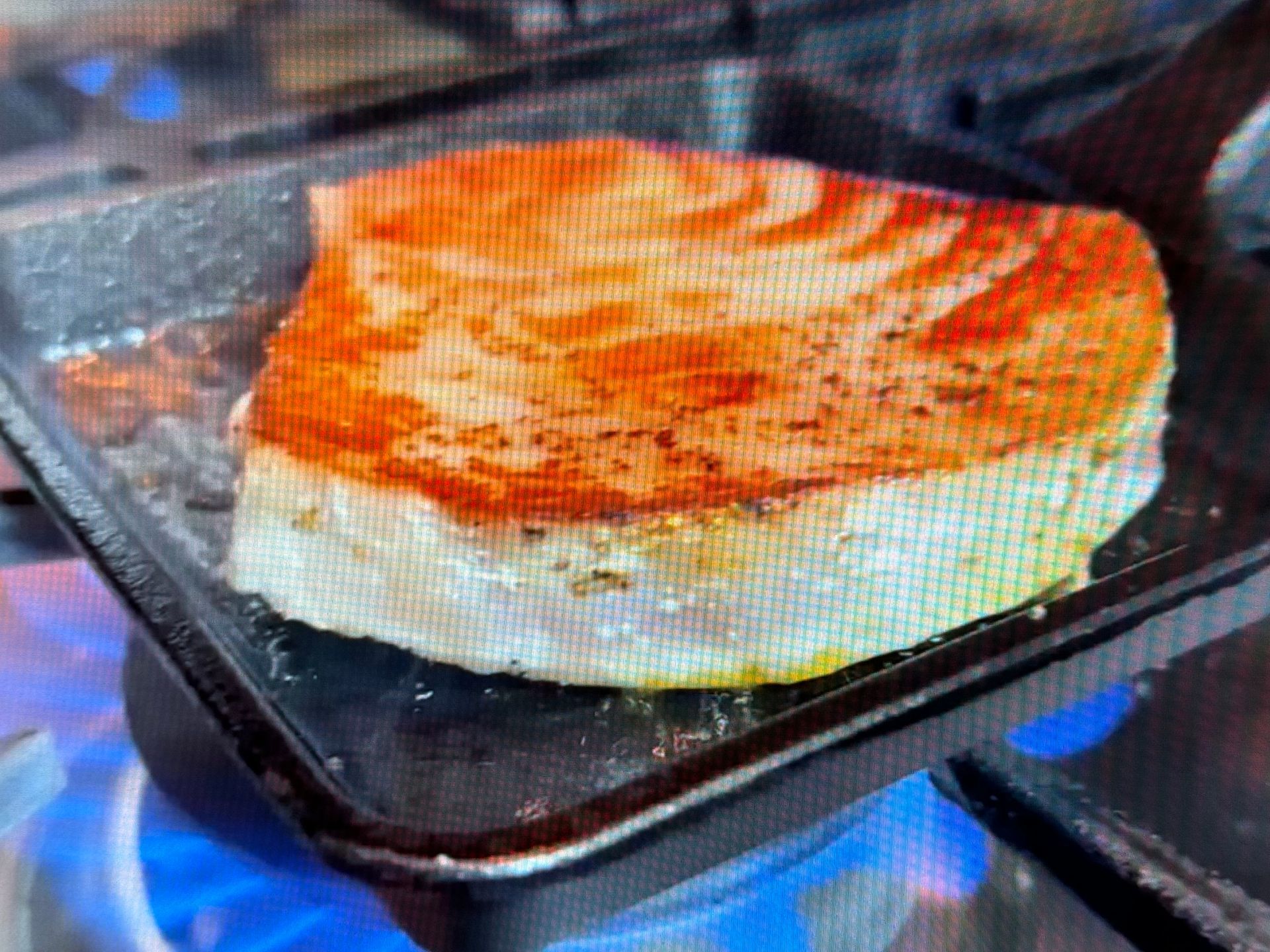 A piece of salmon is being cooked on a pan on a stove.