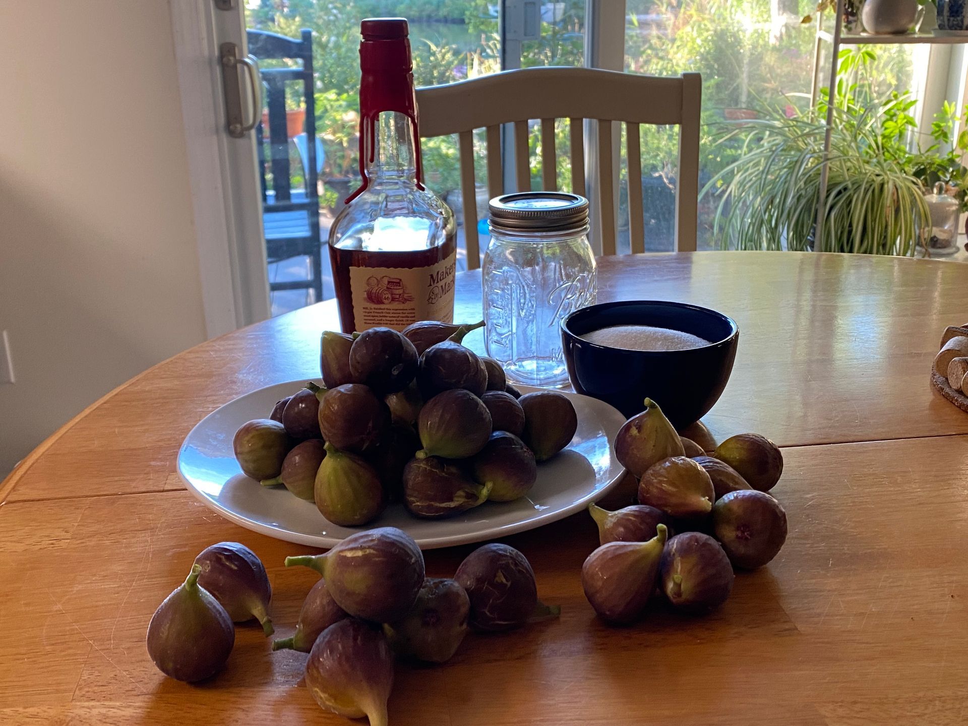 A table with a plate of figs and a bottle of bourbon
