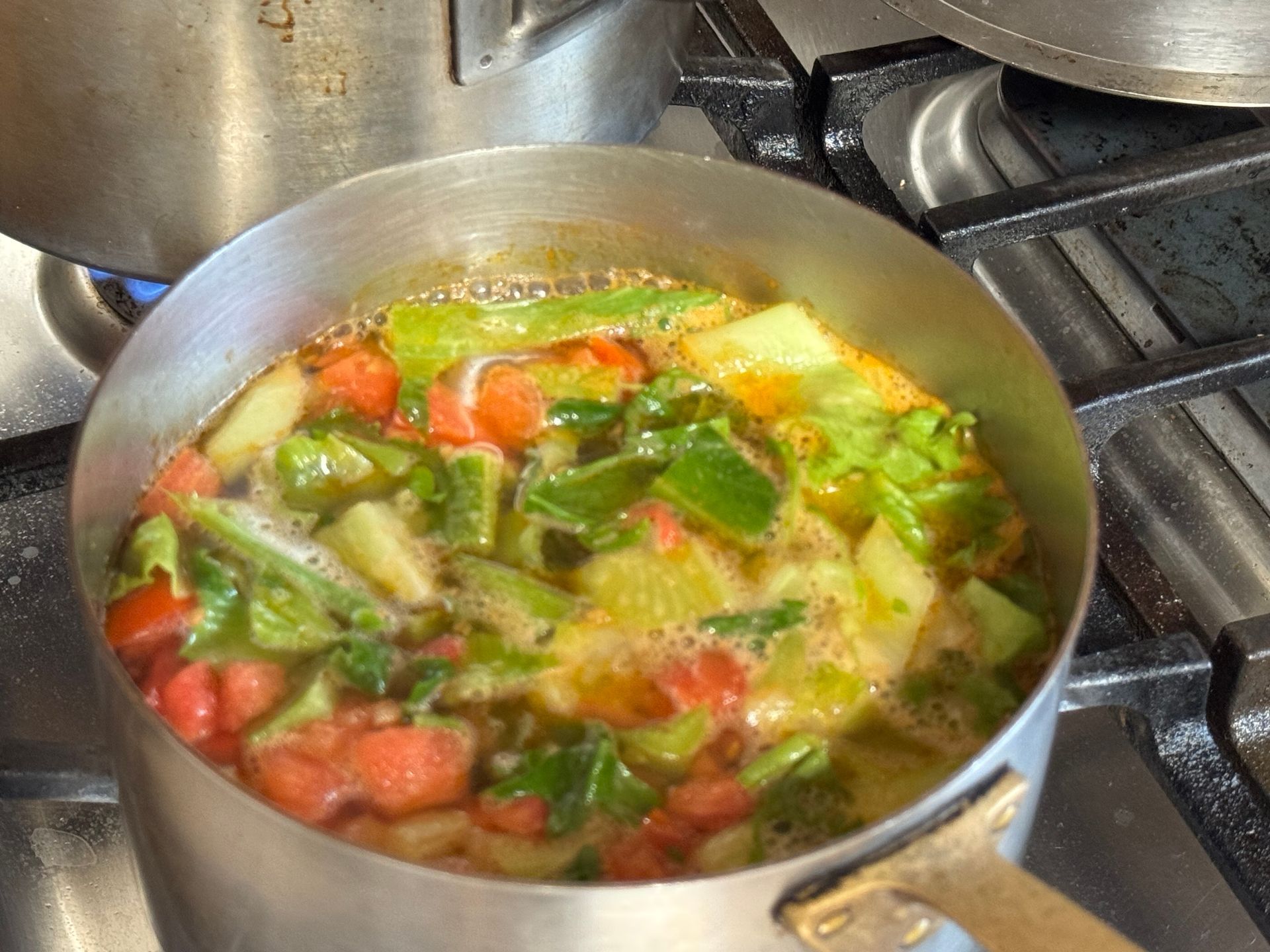 A close up of a bowl of soup with shrimp and potatoes.
